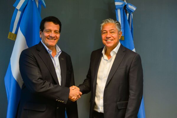 Felipe Bayon, CEO de GeoPark, y Rolando Figueroa, Gobernador del Neuquen) de Neuquén se dan la mano durante el anuncio del aporte de la compañía al programa de becas “Gregorio Álvarez”, con banderas de Argentina al fondo.